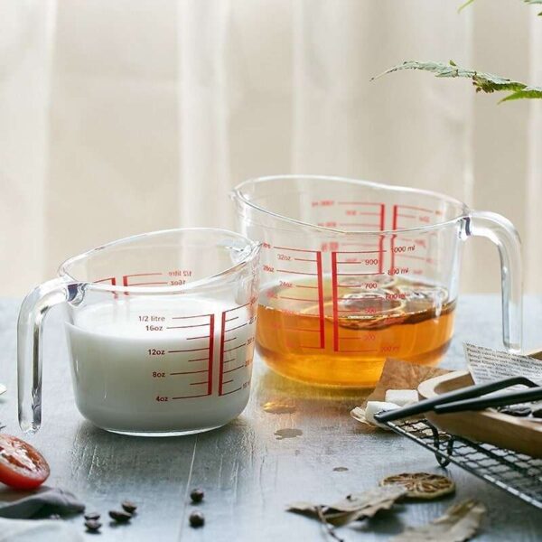 Two glass measuring cups: one containing 400 ml of oil and the other containing 400 ml of milk.