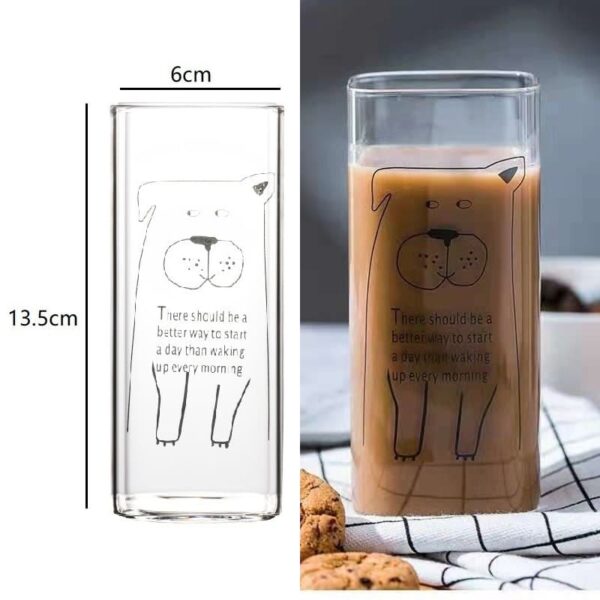 A picture of a person holding a drinking glass with an adorable dog design printed on it. Below the dog, there is a positive message that reads 'There should be a better way to start a day than waking up every morning.' The glass contains coffee on one side, while the other side displays clear measurements.