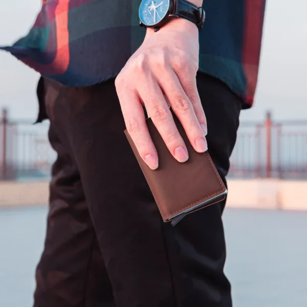 Man holding a coffee-colored RFID wallet.